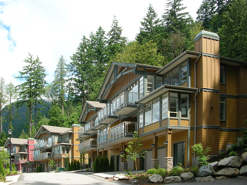 front view of luxury townhome complex with large trees in the background